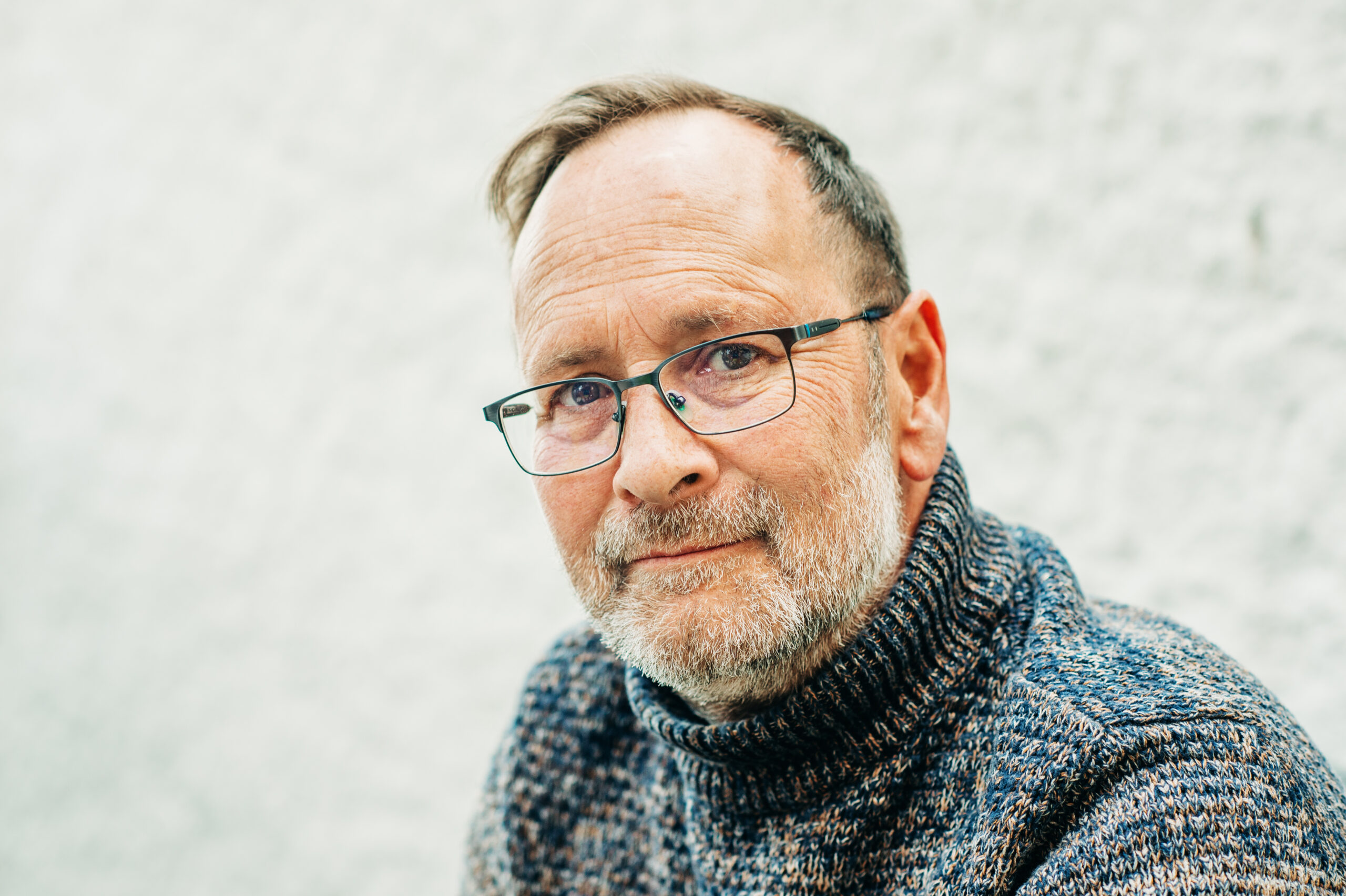 Outdoor portrait of 50 year old man wearing brown pullover and eyeglasses